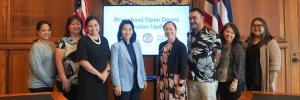 group of people stand in front of sign that says "preschool open doors expansion updates"