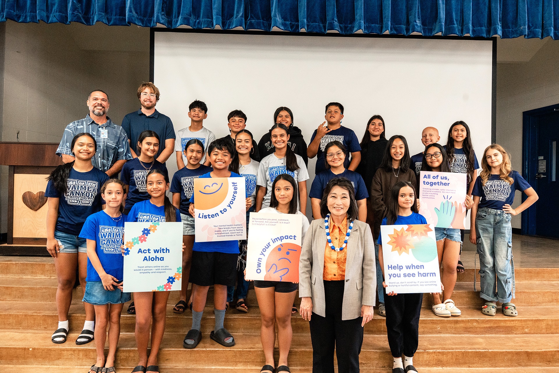 Lt. Gov. Luke standing with middle school students from Waimea Canyon Middle School holding various posters relating to Digital Aloha Month.